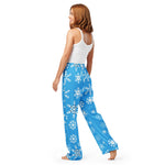 Woman wearing blue snowflake-patterned pants on a white background